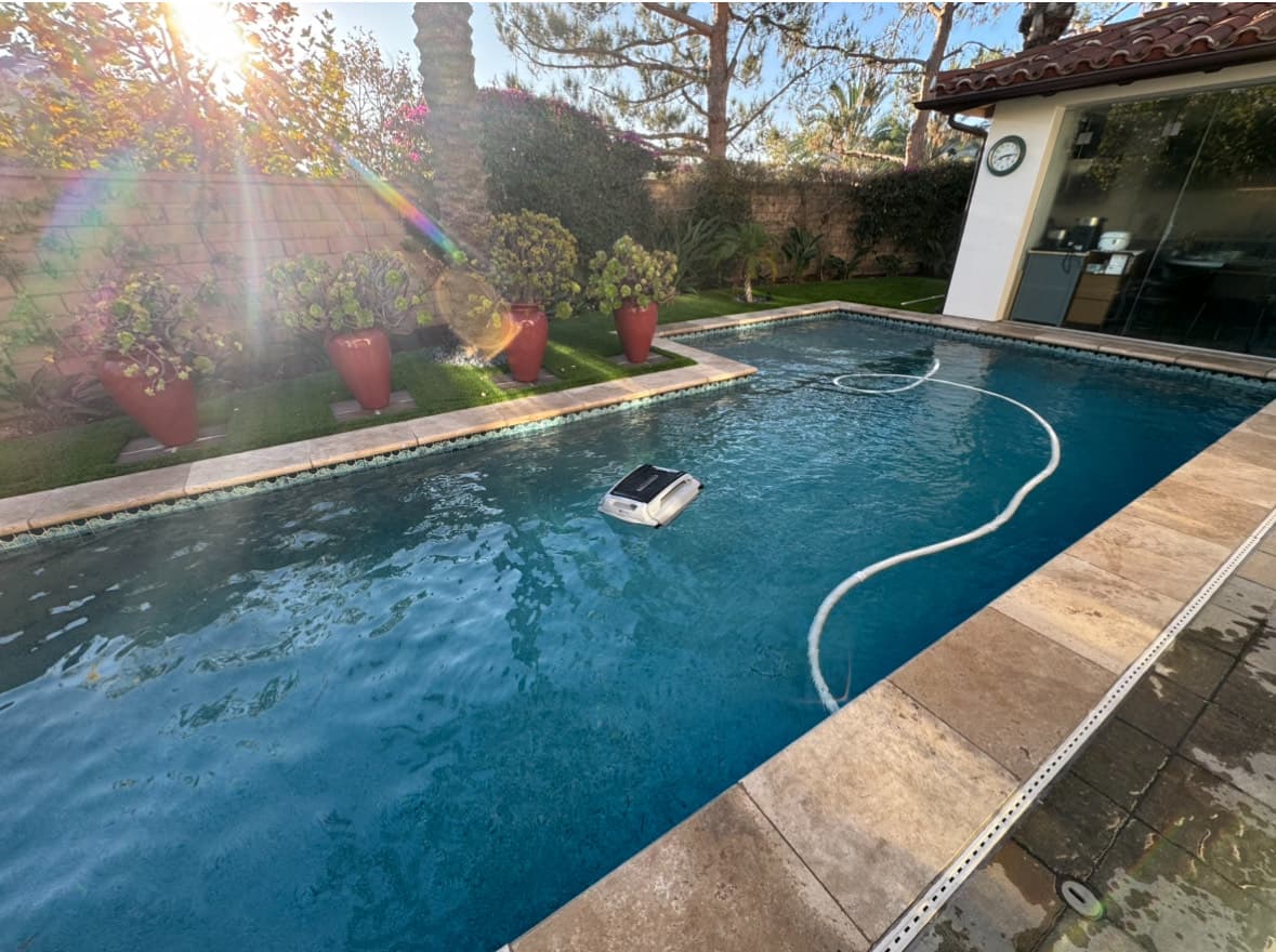 Pool cleaning service with robotic cleaner in backyard pool